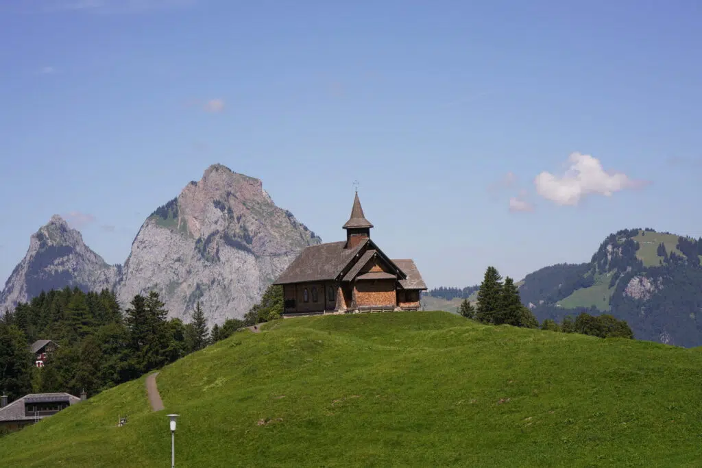 A picturesque wooden church set against a backdrop of dramatic mountain peaks.